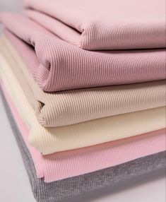 four folded pink and white sweaters are stacked on top of each other in different colors