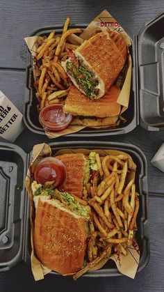 two trays filled with sandwiches and fries next to a cup of ketchup