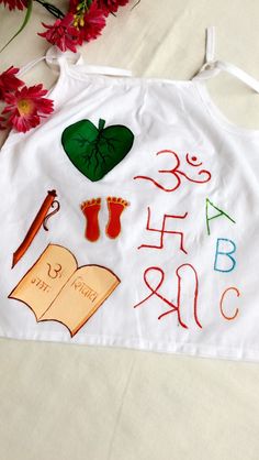 a white apron with writing on it next to red flowers and a pair of scissors