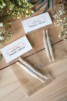 two toothbrushes sitting on top of a wooden table next to some cards and flowers