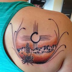 a woman with a tattoo on her shoulder and the sun in the sky behind her