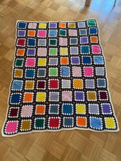 a crocheted blanket is on the floor in front of a chair and table