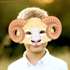 a young boy wearing a paper mask with ram's head cut out to make it look like he is smiling