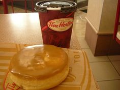 a donut sitting on top of a table next to a cup of coffee in a restaurant