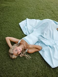 a beautiful woman laying on top of a lush green field