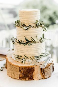 a white wedding cake with greenery on top