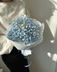 a woman holding a bouquet of blue flowers