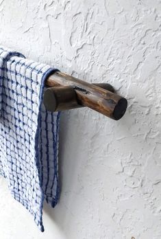 a towel hanging on the side of a white wall next to a wooden pole with a hook