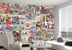 a living room filled with white furniture and lots of comic characters on the wall behind it