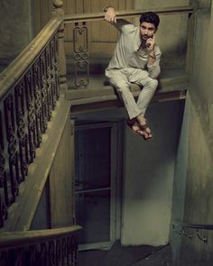 a man is hanging upside down on the stairs while talking on his cell phone in an abandoned building