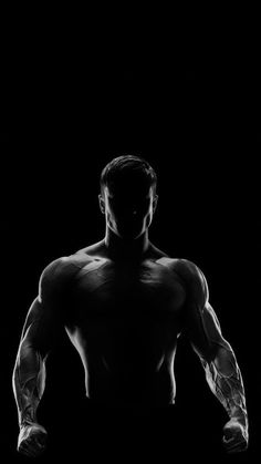 a man with muscles standing in the dark