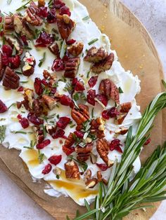 a pizza with cream cheese, cranberries and pecans on it sitting on top of a cutting board