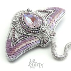 a pink and silver brooch with an intricate design