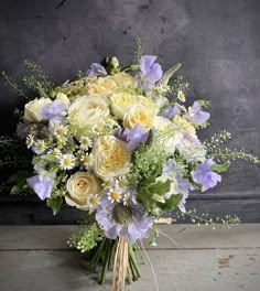 a bouquet of flowers sitting on top of a wooden table next to a black wall