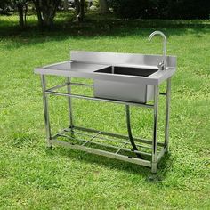 a stainless steel sink sitting on top of a grass covered field