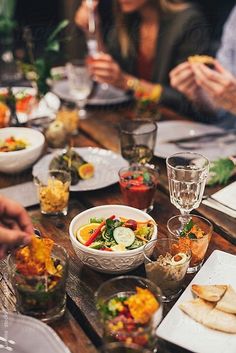 people sitting at a table with plates and bowls of food in front of them,