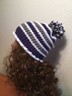 a woman with curly hair wearing a knitted hat