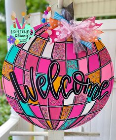 a colorful welcome sign hanging from the side of a white porch chair with pink and blue accents