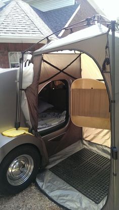 an outdoor tent with the door open to show it's bed and sidewalls