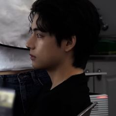 a young man sitting in front of a laptop computer on top of a desk next to a pillow