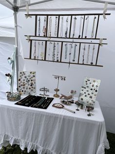 a table topped with lots of necklaces under a white tent covered by a tarp