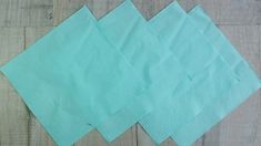 four pieces of green paper sitting on top of a wooden floor