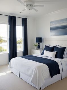 a bedroom with white walls, blue curtains and a large bed in front of two windows