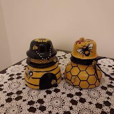 two yellow and black honey jars sitting on top of a doily covered tablecloth