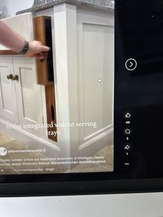 a person is opening the door to a white kitchen cabinet that has drawers on each side