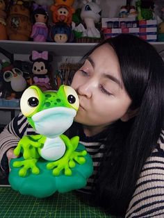 a woman kissing a frog toy on top of a table