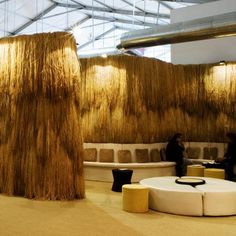 two people are sitting at tables in a room with hay covering the walls and floor