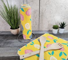 a wooden spoon and fork sitting on top of a yellow towel next to a potted plant