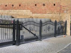 a black gate is in front of a brick wall