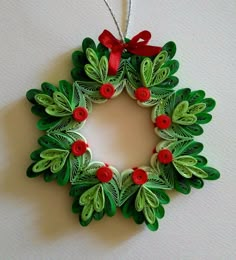 an ornament made out of paper with red buttons and green leaves on it