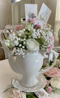 a white vase filled with lots of flowers sitting on top of a table covered in cards