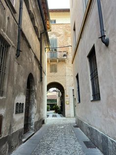 an alley way with cobblestone pavement between two buildings