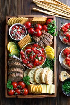 a wooden tray filled with different types of food and breads on top of it