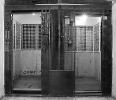 an old jail cell with two doors and bars on the sides, in black and white