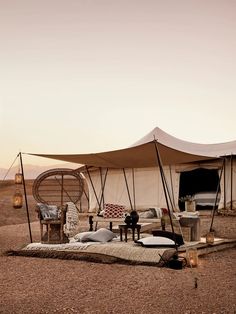 a tent set up in the desert with furniture