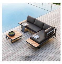 a couch and coffee table on a wooden deck next to a pool with water in the background