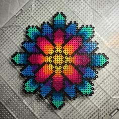 an image of a colorful flower made out of perfored beads on the floor