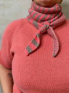 a woman wearing a pink sweater with a scarf around her neck