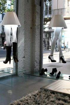 a pair of high heeled shoes are reflected in a mirror on the floor next to a lamp