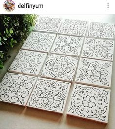 some white tiles sitting on top of a table next to green plants and bushes with the words delfifyum written above them