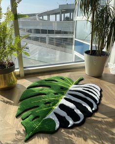 a large green leaf rug sitting on top of a wooden floor next to a window