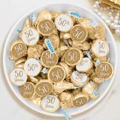 a white bowl filled with gold foiled chocolates next to a golden bag of candy