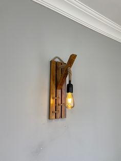 a light that is on the wall next to a wooden beam with a light bulb hanging from it