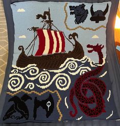 a crocheted pillow with an image of a boat and sea creatures on it