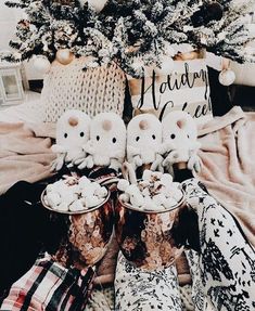 two little white kittens sitting on top of some boots next to a christmas tree