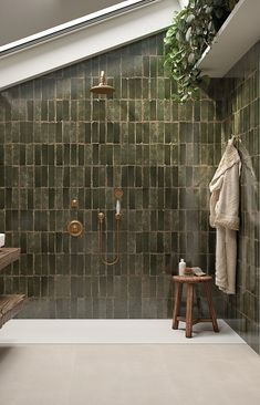 a bathroom with green tiled walls and flooring next to a bathtub, shower head, and sink